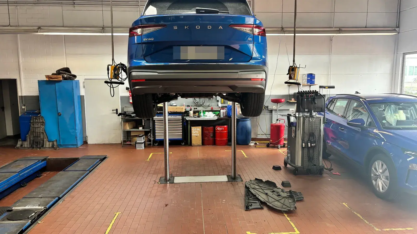 Werkstatt in Wiesloch: Halle des Automobilsalon Bellemann mit einem ŠKODA Enyaq auf der Hebebühne, Werkzeugwagen und einem zweiten Arbeitsplatz daneben