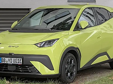 BYD Dolphin Surf Test: limettengrüner Elektro-Kleinwagen von schräg vorn, geparkt vor einem grauen Gebäude