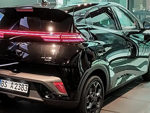 BYD Dolphin Surf Versicherung: schwarzer Elektro-Kleinwagen von schräg hinten, angeschlossen an ein Ladekabel