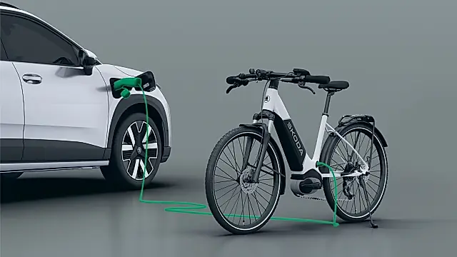 Skoda Epiq bidirektionales Laden per V2L: weißer Epiq lädt über ein Kabel am Ladeanschluss ein Škoda-E-Bike