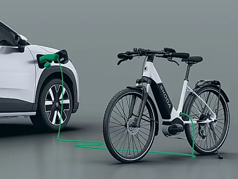 Skoda Epiq bidirektionales Laden per V2L: weißer Epiq lädt über ein Kabel am Ladeanschluss ein Škoda-E-Bike