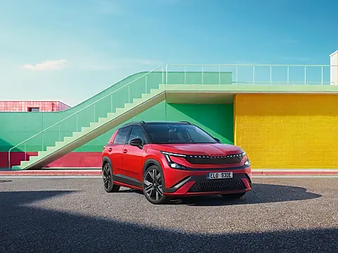 Škoda Epiq Sportline in Rot mit schwarzem Dach: schräg von vorn mit leuchtendem Lichtband vor bunten Mauern