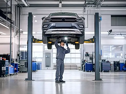 Kompaktes SUV auf der Hebebuehne, ein Mechaniker prueft den Unterboden – Thema Skoda Karoq Probleme und TUEV-Report